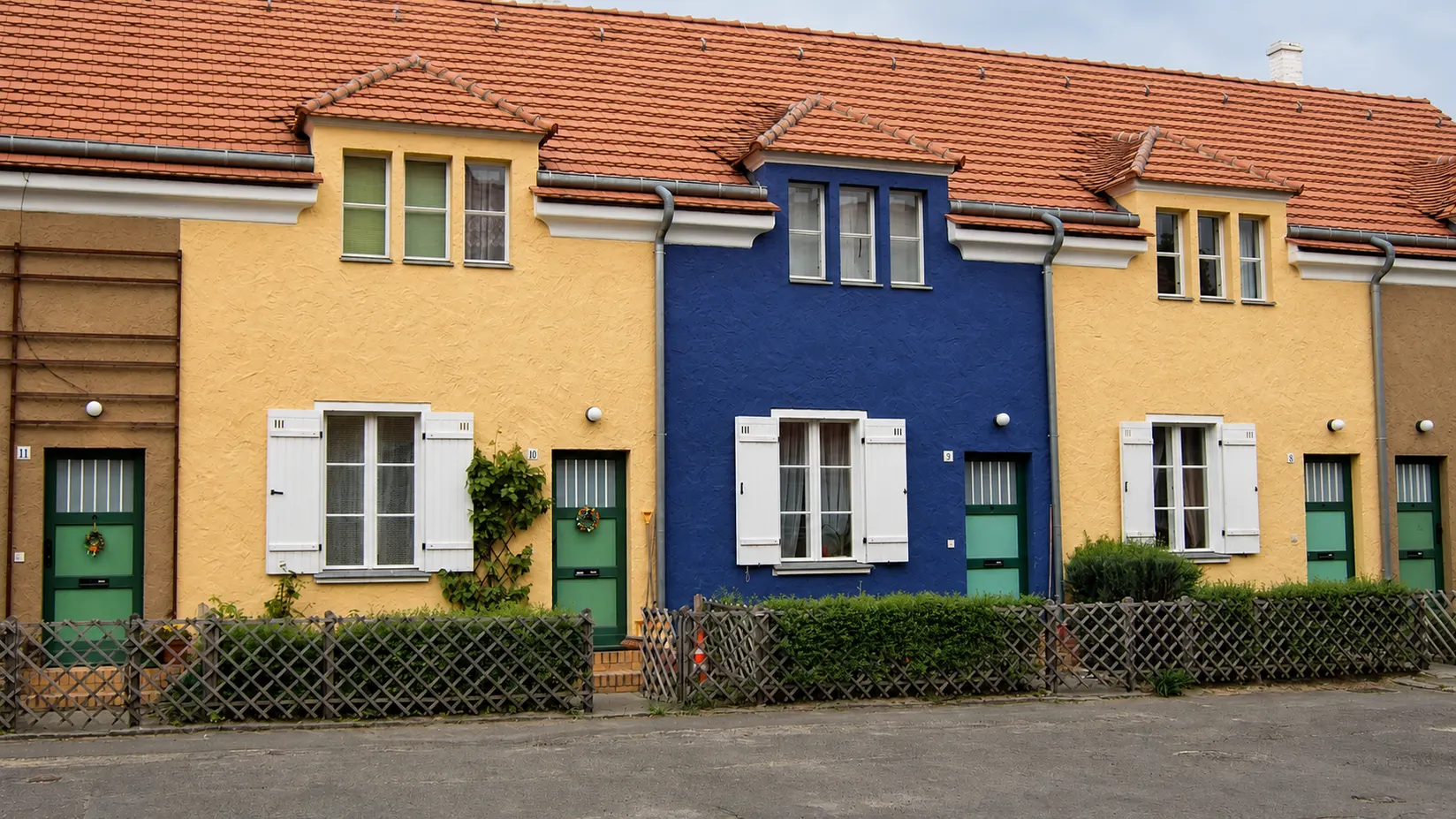 Reihenhäuser der Tuschkastensiedlung mit gelben und blauen Fassaden und roten Dächern.